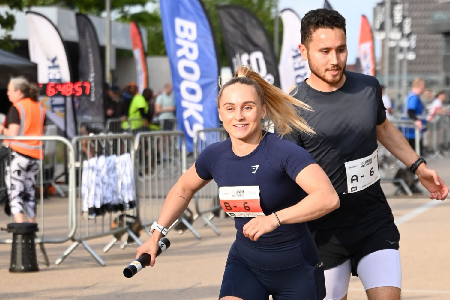 Runners exchanging a relay baton during RunThrough Relays London at Queen Elizabeth Olympic Park, celebrating teamwork and Global Running Day.