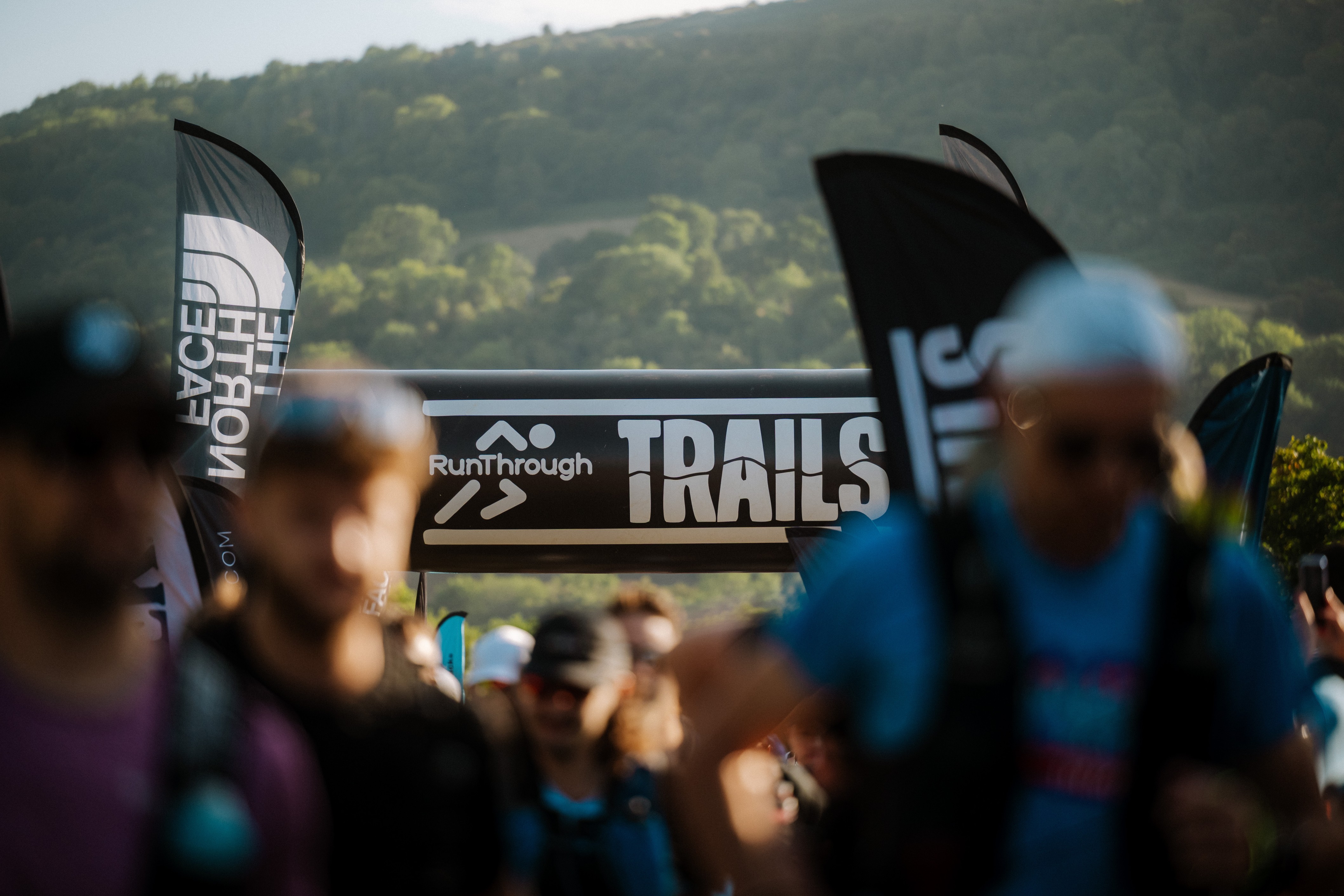 Runners at a RunThrough Trails event in the Brecon Beacons, with RunThrough Trails and The North Face branding visible in the event village.